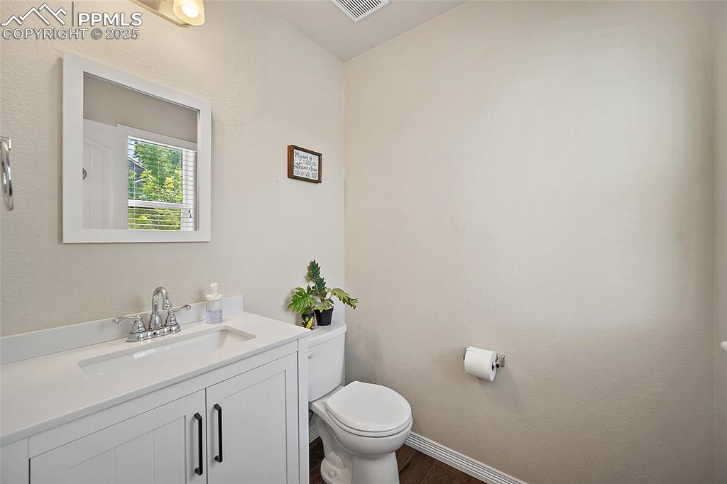 Image 5 of 38: Half bath featuring vanity, a textured wall, and dark wood-style flooring