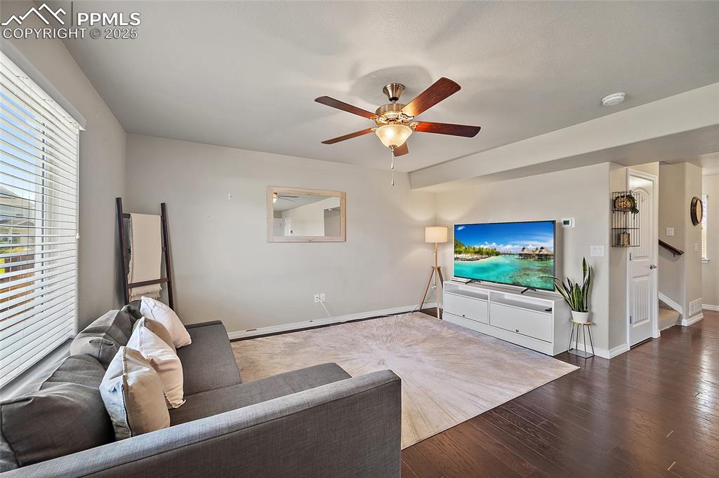 Image 8 of 38: Living room with wood finished floors and ceiling fan