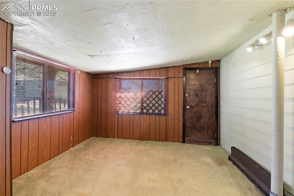 Image 27 of 31: Carpeted empty room featuring wooden walls and vaulted ceiling