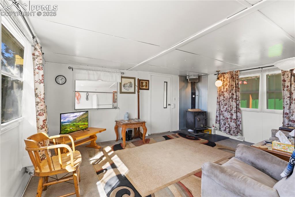 Image 9 of 31: Carpeted living room featuring a wood stove