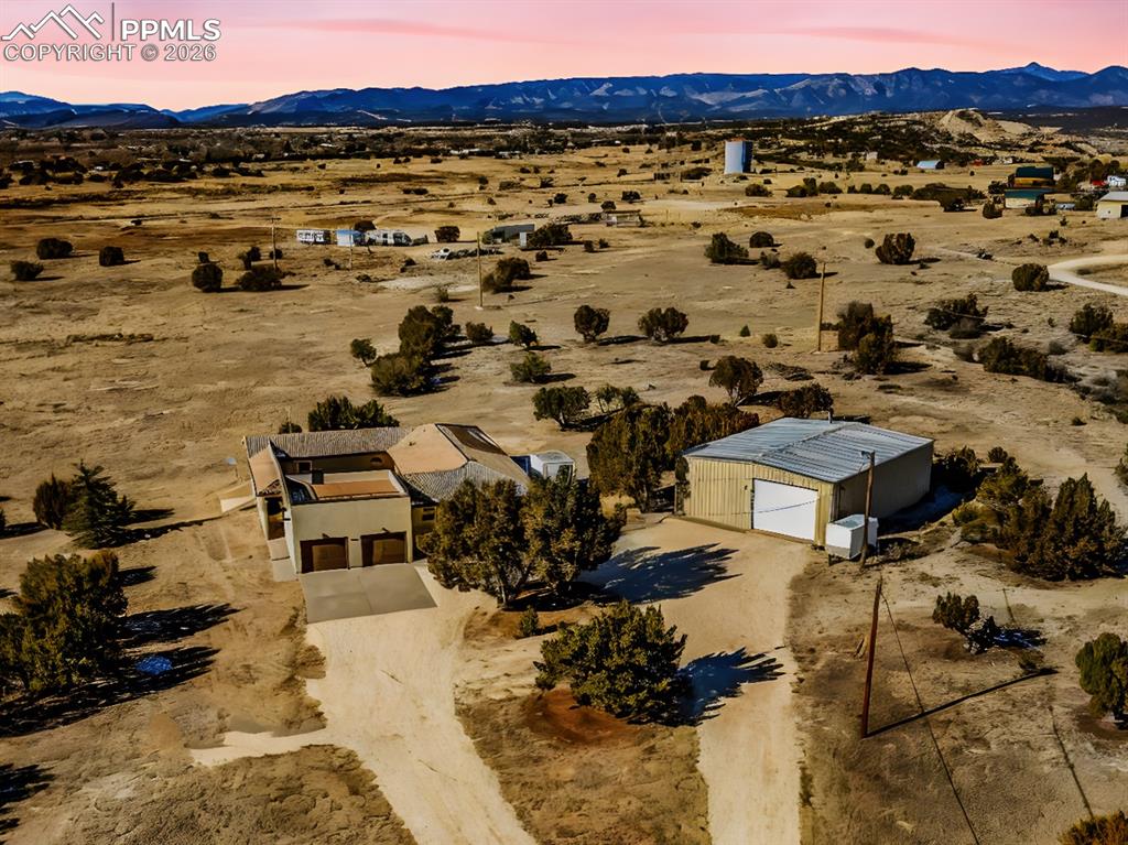 Caption: Front Elevation with Mountain View – Front-facing aerial image of the home and rooftop patio, with u