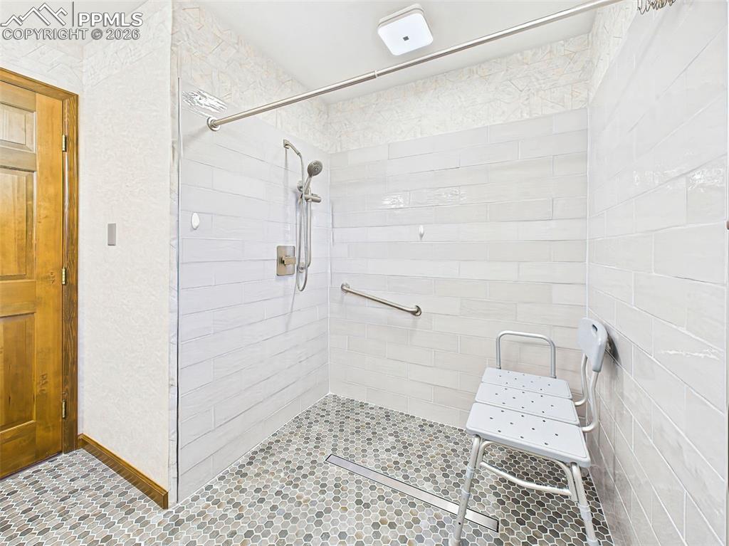 Image 21 of 50: Primary Bath – Shower – Spacious, tiled walk-in shower with grab bars and b