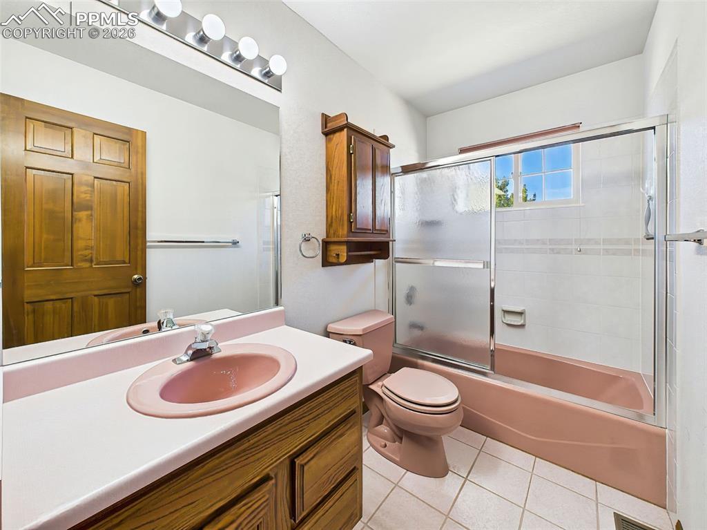 Image 27 of 50: Full bathroom with classic pink fixtures, wood vanity, and sliding glass sh
