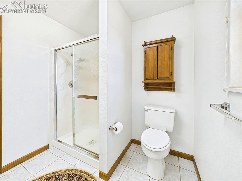 Image 28 of 50: Bathroom – A clean, tiled bath with a step-in shower, wood cabinetry, and b