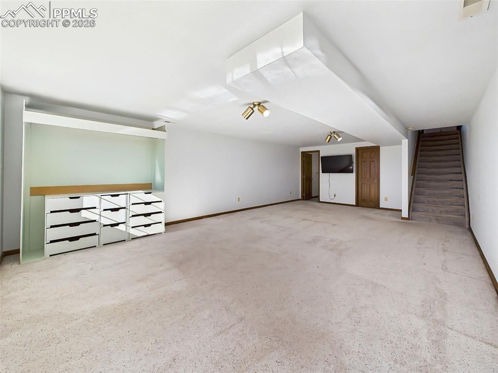 Image 33 of 50: Lower-Level Living Room (Unstaged) – Sunlit lower level with oversized wind