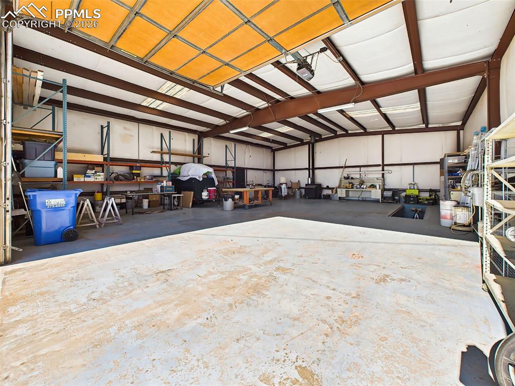 Image 41 of 50: Detached Shop Entry View – Open shop layout with roll-up garage door, workb