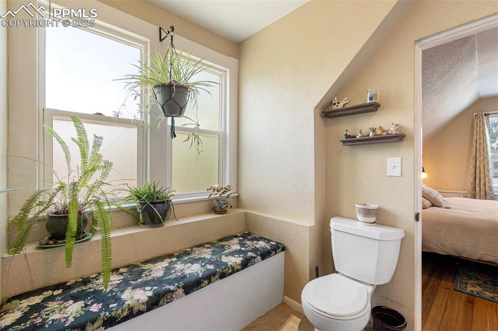 Image 23 of 49: Bathroom featuring a textured wall, connected bathroom, and wood finished f