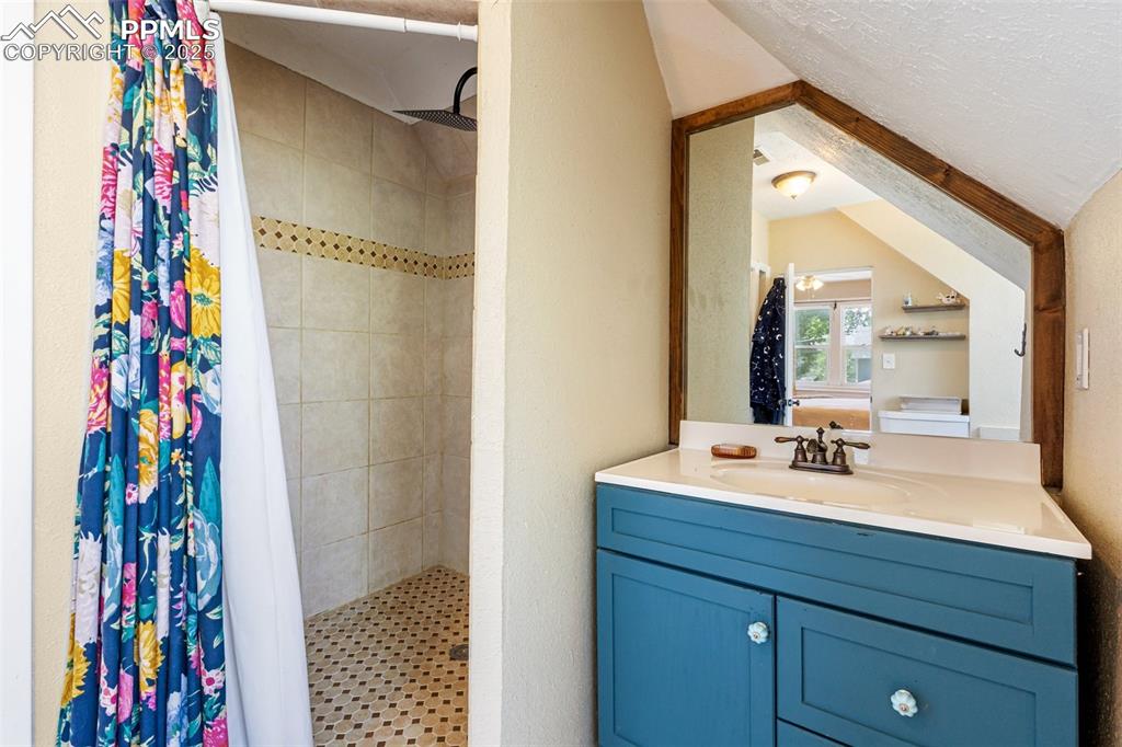 Image 24 of 49: Bathroom featuring a stall shower, vanity, and a textured ceiling