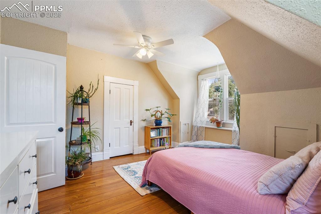 Image 28 of 49: Bedroom with light wood-type flooring, a textured ceiling, vaulted ceiling,