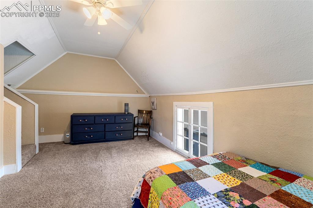 Image 35 of 49: Bedroom featuring a textured wall, carpet floors, a ceiling fan, vaulted ce