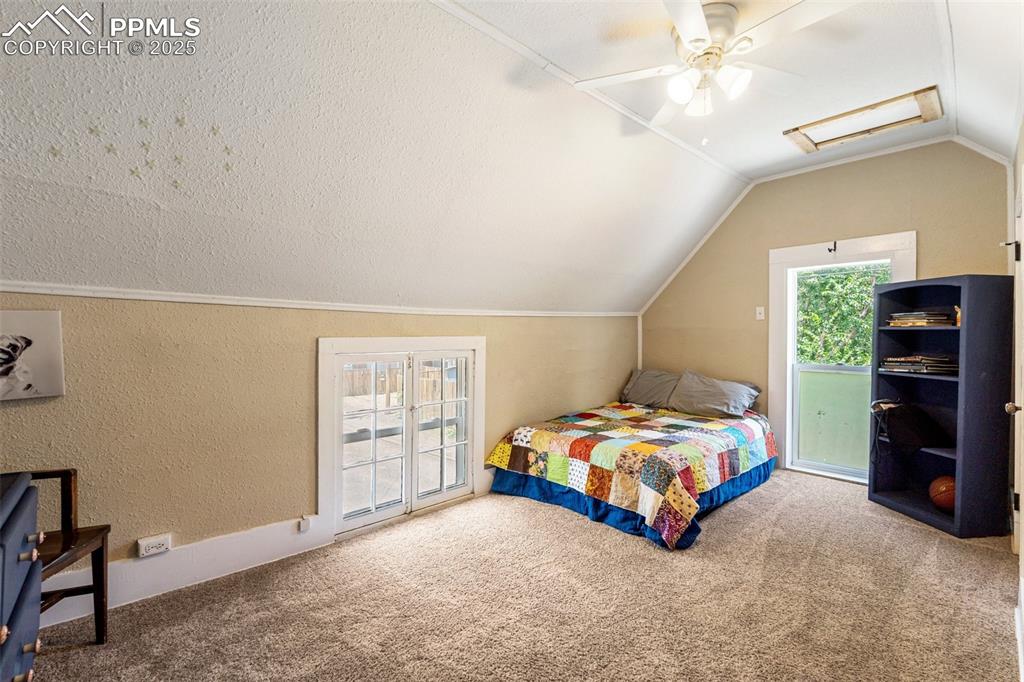 Image 36 of 49: Carpeted bedroom with attic access, a textured wall, vaulted ceiling, acces