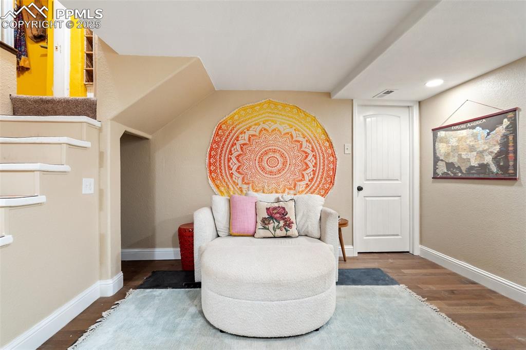 Image 38 of 49: Sitting room with wood finished floors and stairway