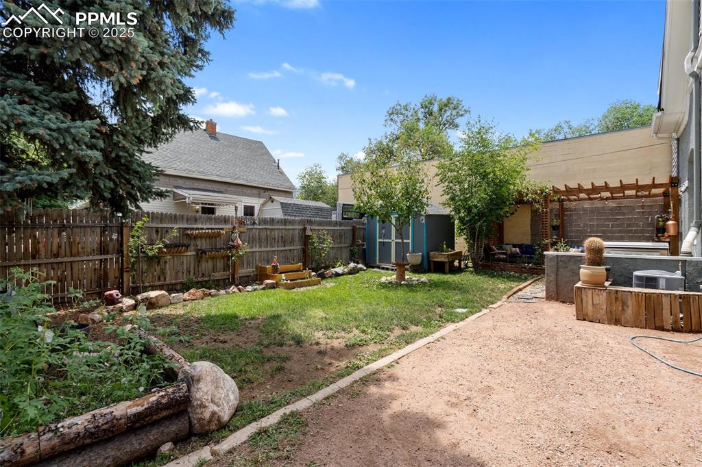 Image 42 of 49: Fenced backyard featuring a pergola, a patio area, a vegetable garden, and 