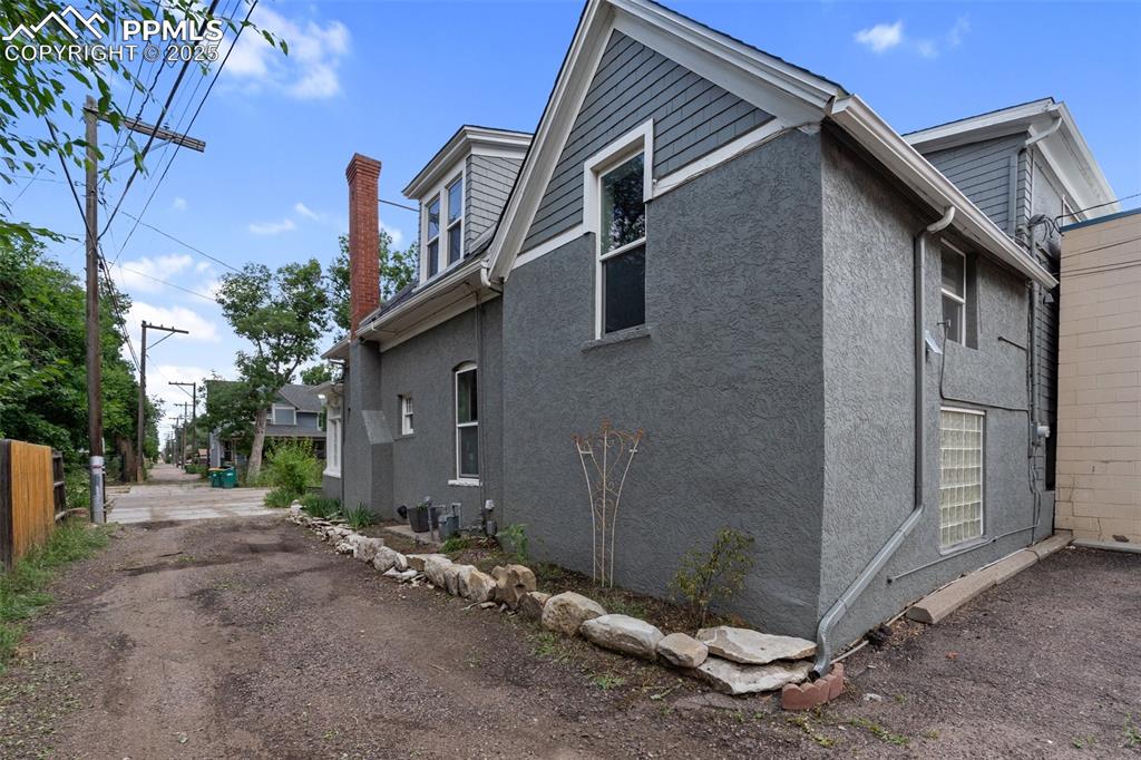 Image 48 of 49: View of side of property with stucco siding and a chimney