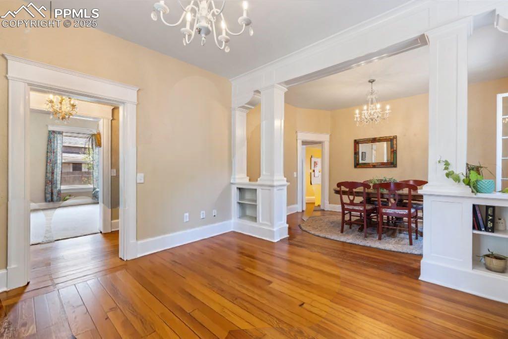 Image 5 of 49: Dining space with a chandelier, decorative columns, and hardwood / wood-sty