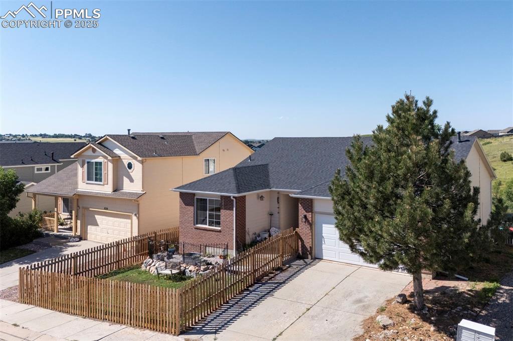 Caption: View of front of home featuring driveway, brick siding, roof with shingles, and a garage