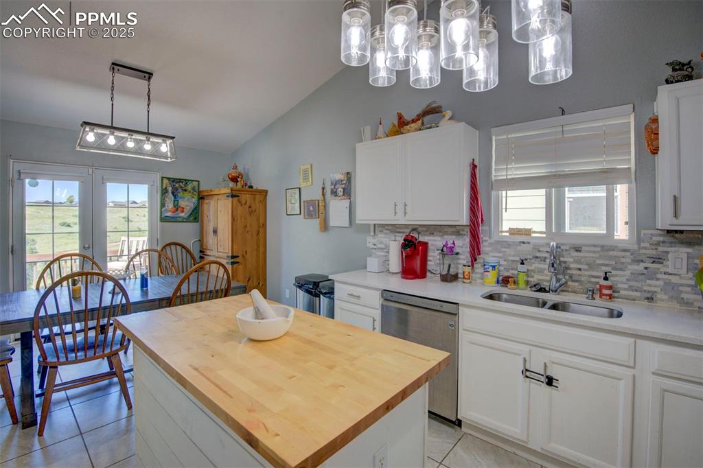 Image 10 of 44: Kitchen with stainless steel dishwasher, vaulted ceiling, wood counters, an