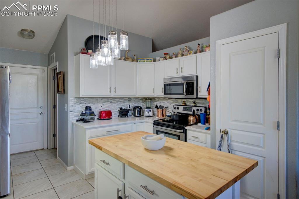 Image 11 of 44: Kitchen with appliances with stainless steel finishes, wooden counters, tas