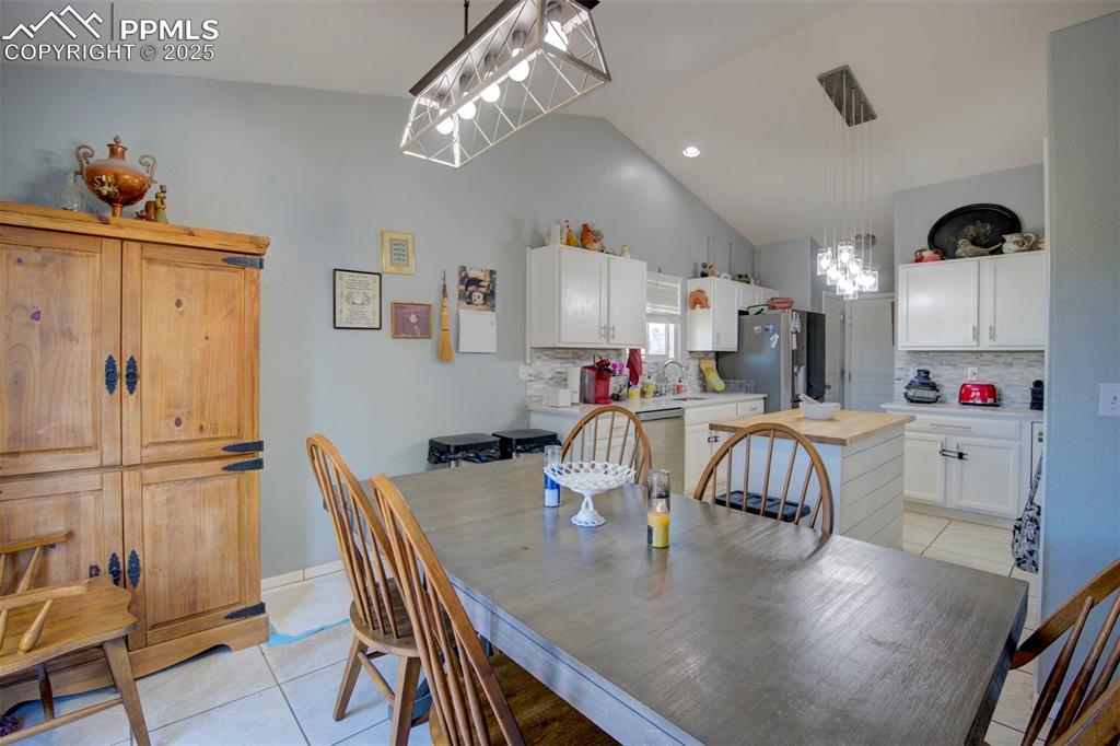 Image 13 of 44: Dining room with a chandelier, light tile patterned floors, and high vaulte