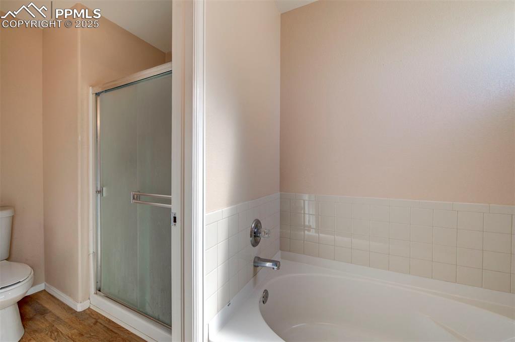 Image 19 of 44: Bathroom with a garden tub, a stall shower, and wood finished floors
