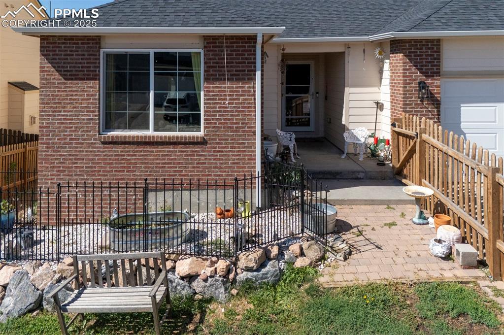 Image 2 of 44: View of exterior entry with brick siding and roof with shingles