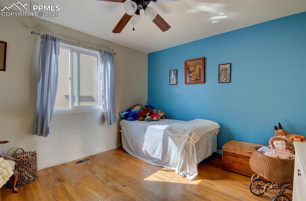 Image 24 of 44: Bedroom with wood finished floors and ceiling fan