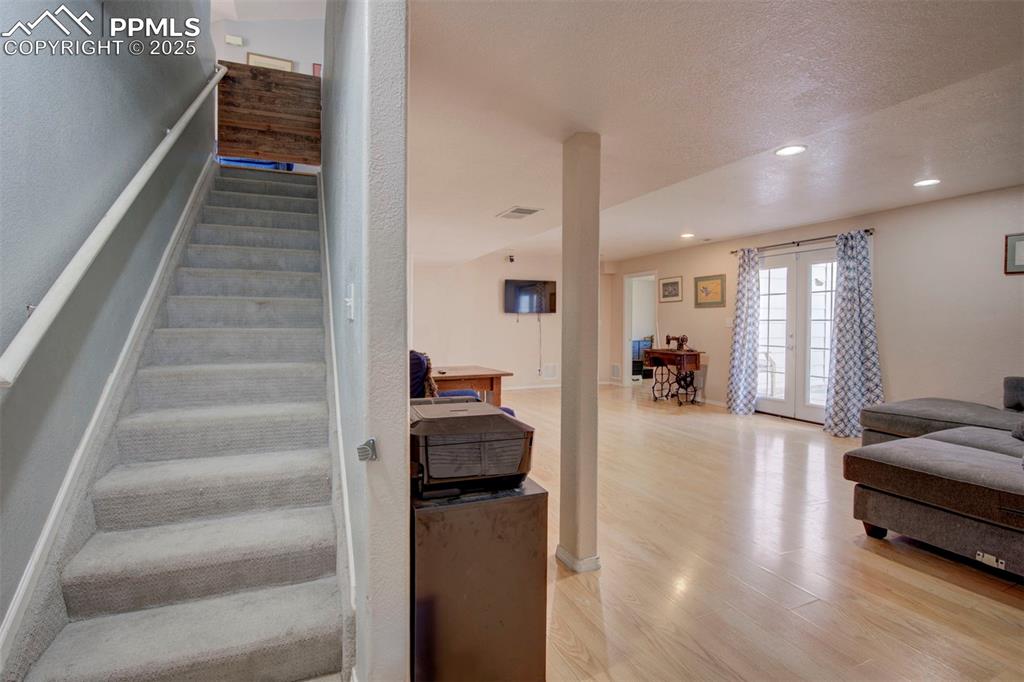 Image 27 of 44: Stairway featuring wood finished floors, french doors, recessed lighting, a