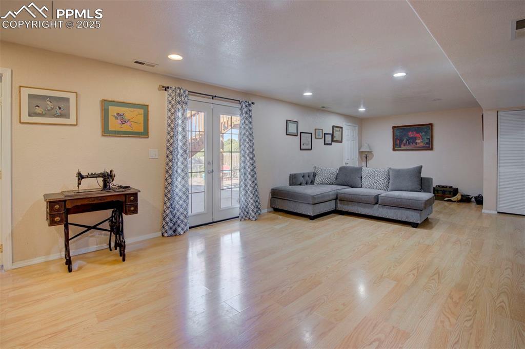 Image 28 of 44: Living room with french doors, wood finished floors, and recessed lighting