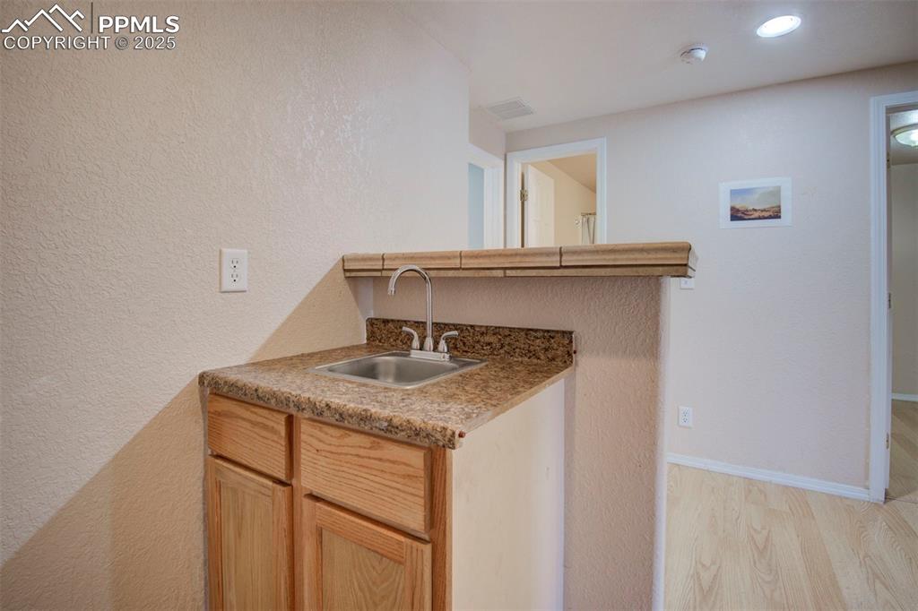 Image 29 of 44: Kitchen with light wood finished floors, a textured wall, and a peninsula