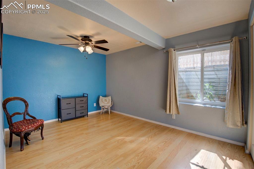 Image 32 of 44: Unfurnished room with wood finished floors, a ceiling fan, and beamed ceili