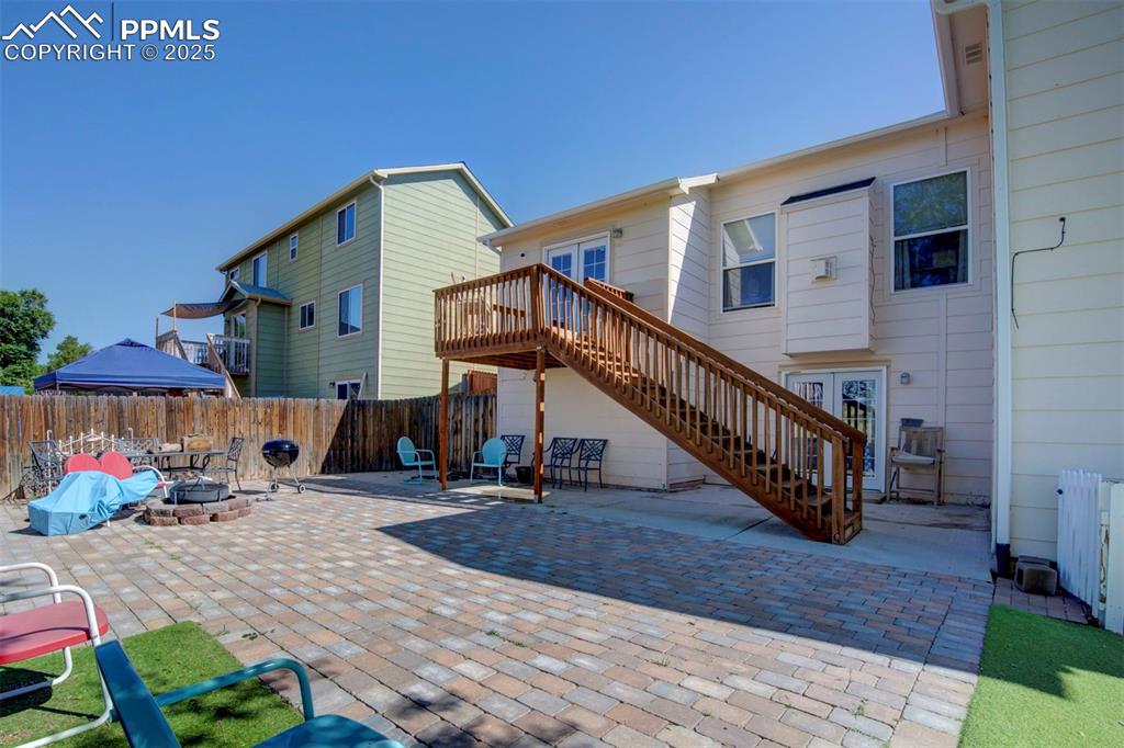 Image 37 of 44: Rear view of house featuring stairway, a fire pit, a patio area, and french