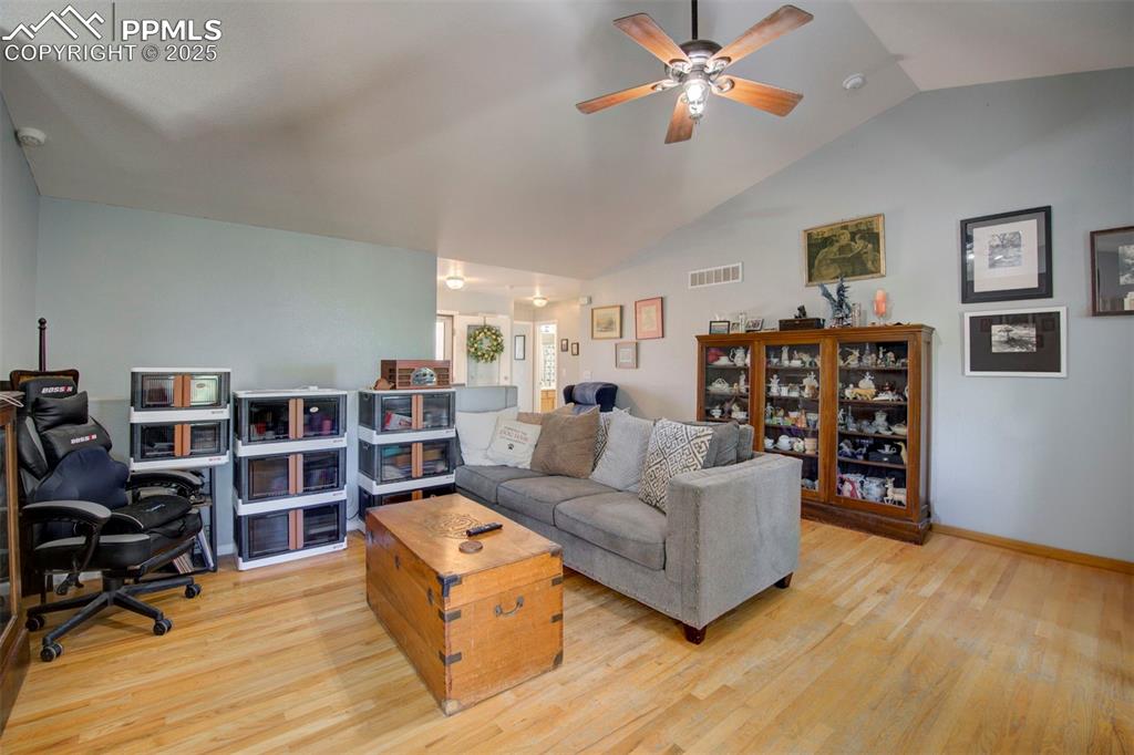 Image 7 of 44: Living room with lofted ceiling, light wood finished floors, a ceiling fan,