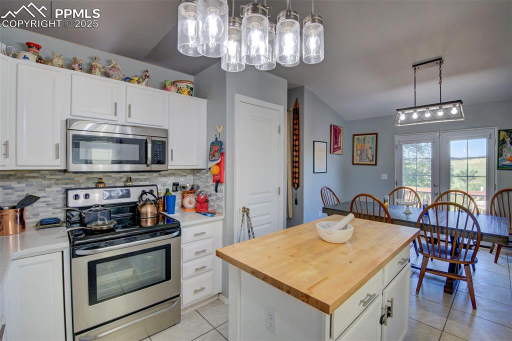 Image 9 of 44: Kitchen with appliances with stainless steel finishes, light tile patterned