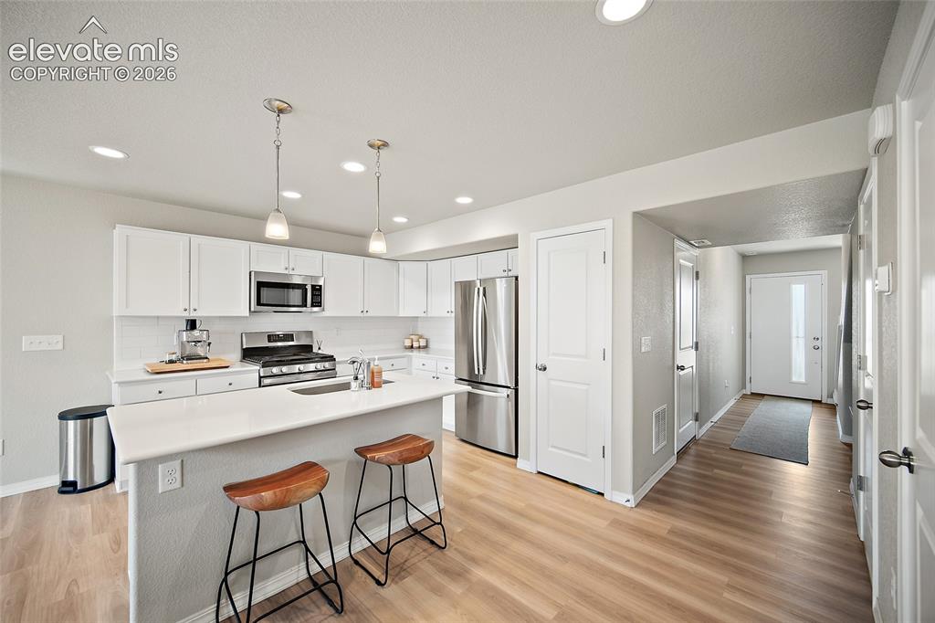 Image 16 of 40: Contemporary kitchen featuring white cabinetry, stainless steel appliances,