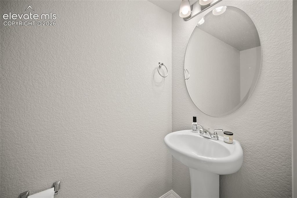 Image 17 of 40: Pedestal sink with chrome faucet, complemented by an oval wall mirror and a