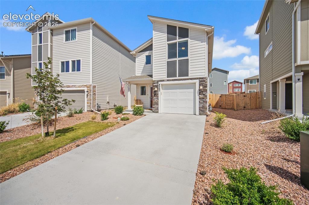 Image 2 of 40: Modern two-story residence featuring light gray siding, stone accents, a si