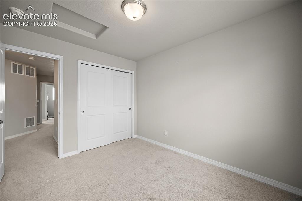 Image 20 of 40: Room featuring neutral-toned carpeting, white baseboards, and light gray wa