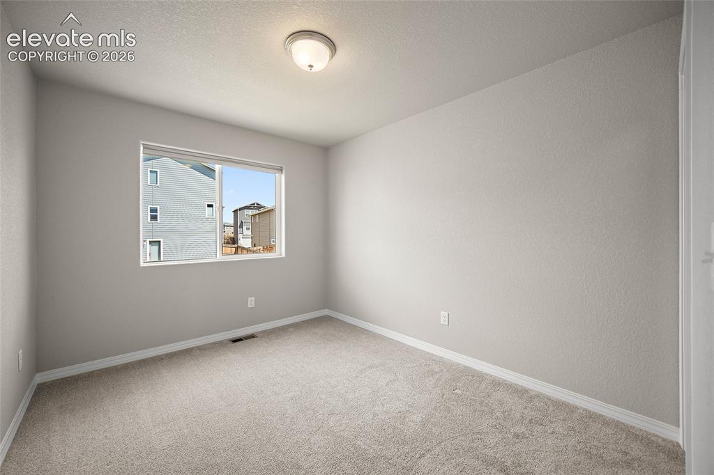 Image 21 of 40: Carpeted room with a single window, neutral wall paint, white trim, and a s