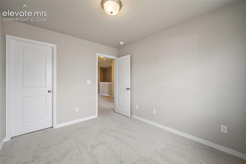 Image 22 of 40: Neutral wall paint, light gray carpeting, and white baseboards