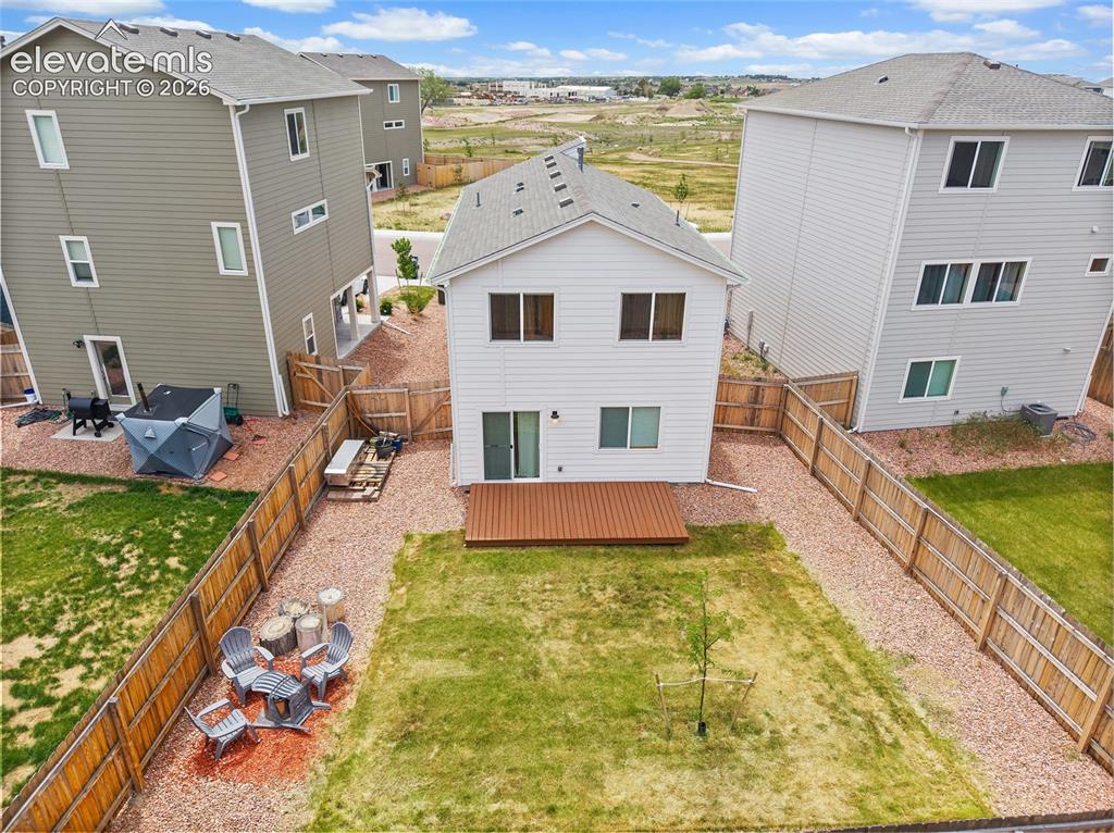 Image 38 of 40: Fenced backyard featuring a wood-finish deck, a gravel perimeter, and a cen