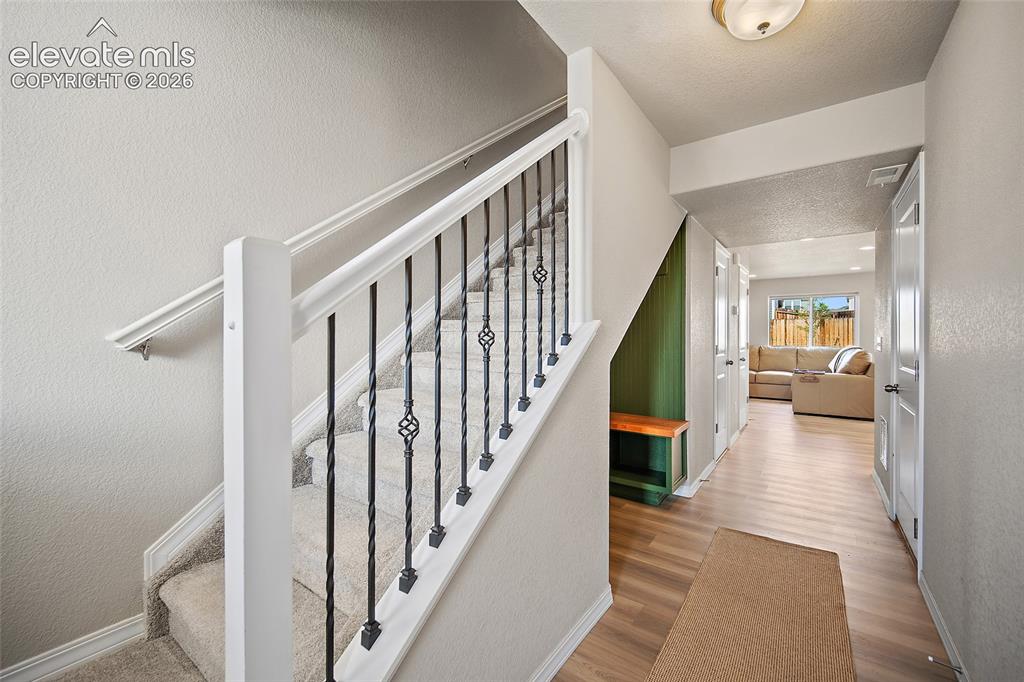 Image 4 of 40: Carpeted staircase featuring wrought iron balusters and a white handrail