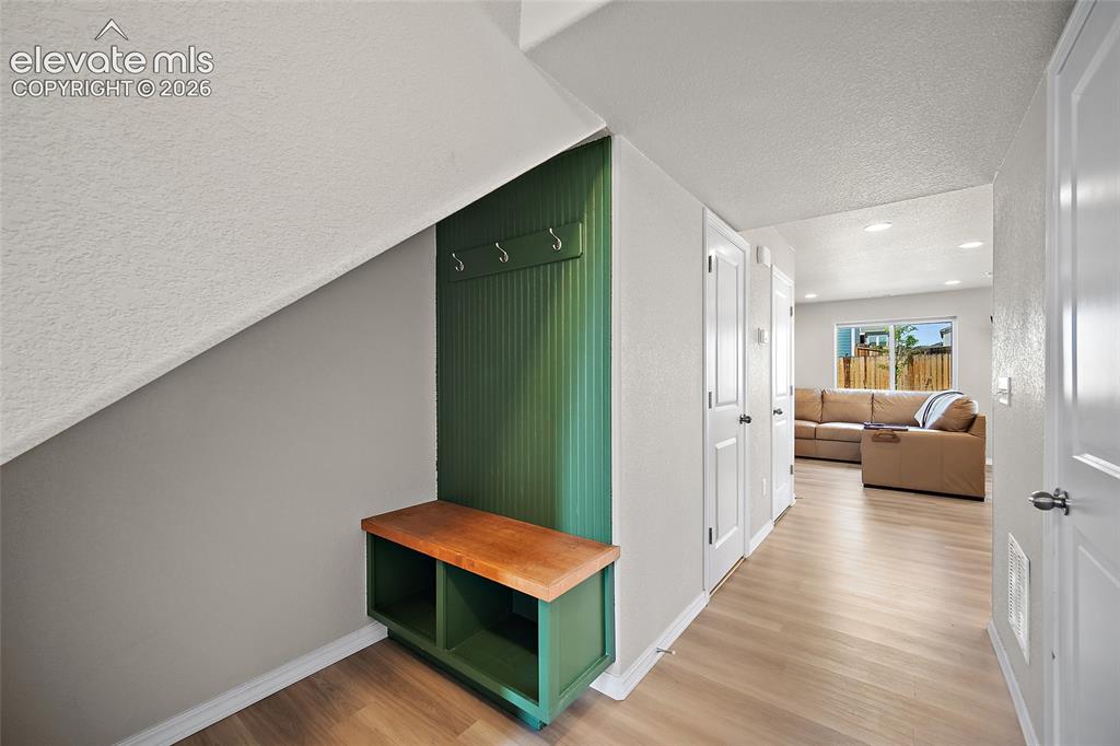 Image 5 of 40: Entryway with wood-finish flooring, built-in green beadboard bench with sto