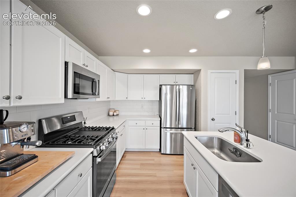 Image 9 of 40: Modern kitchen featuring white cabinetry, stainless steel appliances, light