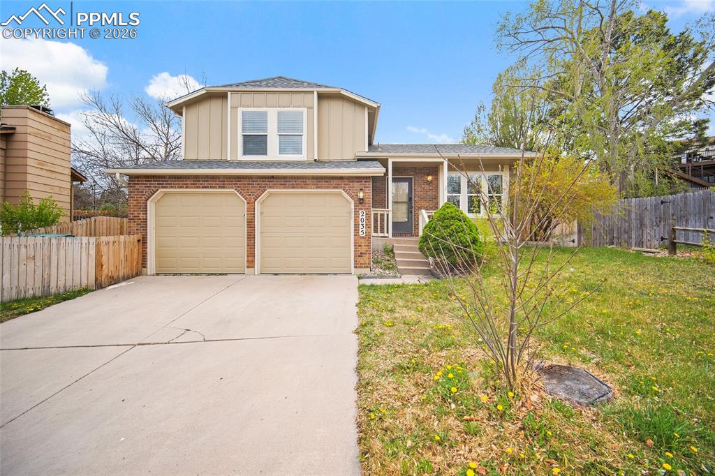 Image 1 of 36: Two-story residence featuring a brick facade and tan siding, a two-car gara