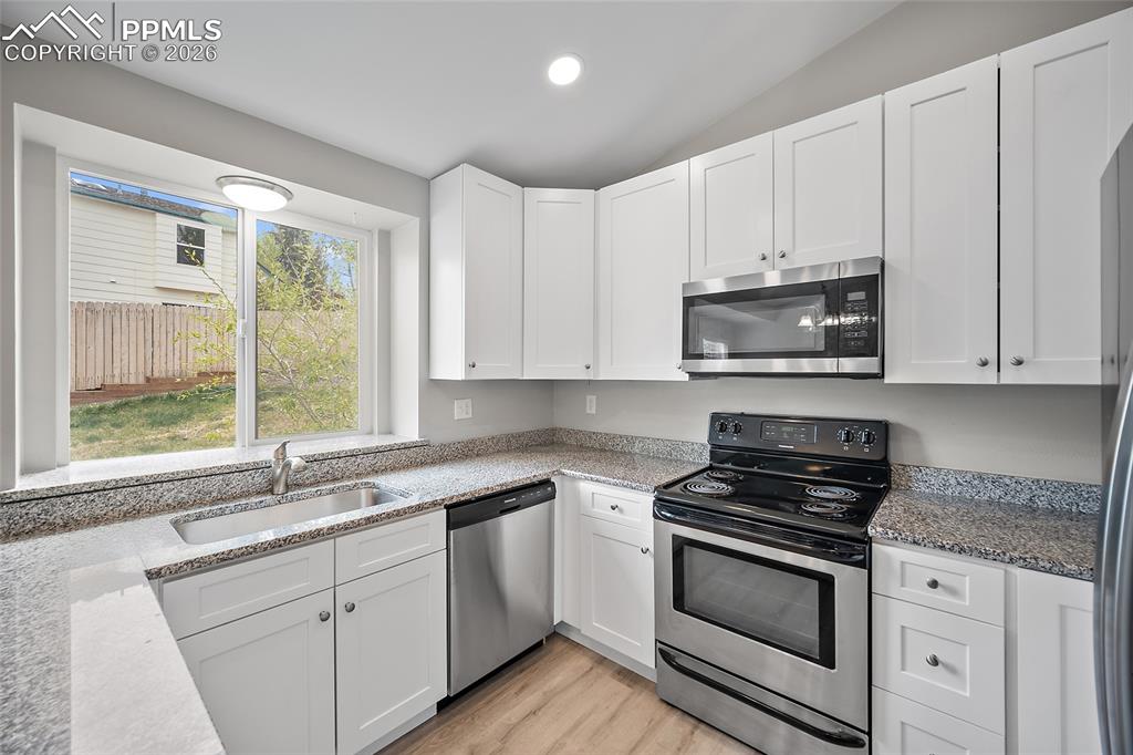 Image 10 of 36: Well-appointed kitchen featuring white cabinetry, granite-finish countertop