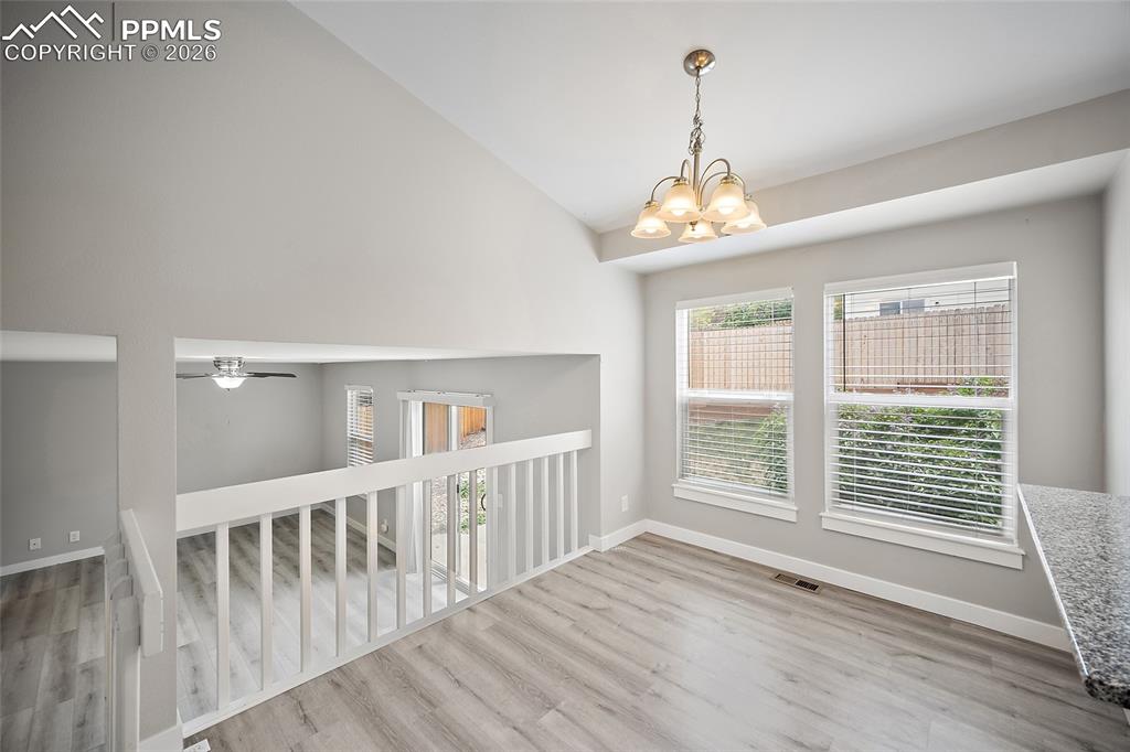 Image 11 of 36: Vaulted ceiling with a decorative chandelier, two large windows with blinds