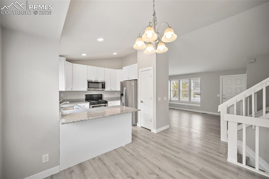 Image 12 of 36: Kitchen featuring white cabinetry, granite-finish countertops, and stainles