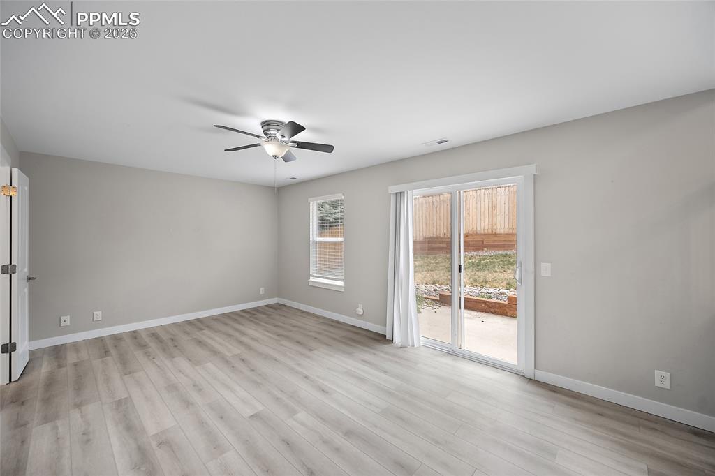 Image 13 of 36: Spacious room featuring wood-finish flooring, a contemporary ceiling fan, a