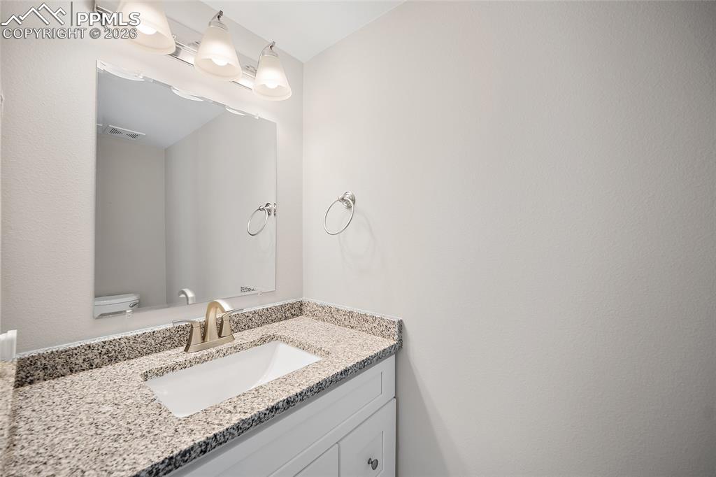 Image 15 of 36: Bathroom vanity featuring a speckled countertop, undermount sink, and a bru