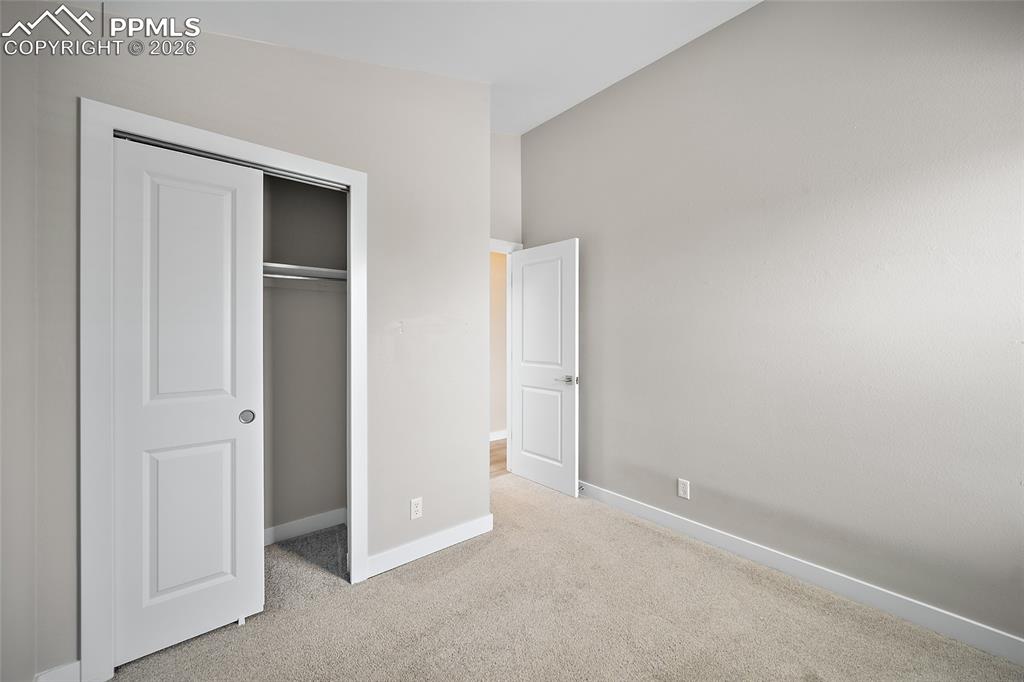 Image 22 of 36: Neutral-toned bedroom featuring a bi-fold closet with an interior rod and s